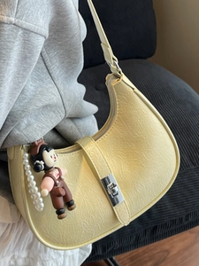 Chic pale yellow hobo bag with pleated texture and pearl pendant on shoulder