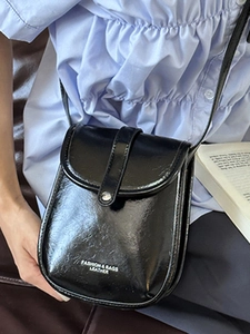 Glossy black crossbody flap bag with fashion text for women in a casual lifestyle setting