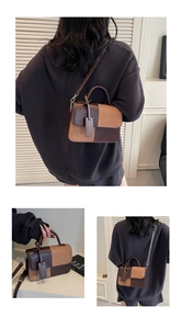 Detail of color-block leather crossbody bag showing dual textures and top handle