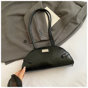 Close-up of black crocodile embossed crescent underarm bag with metallic logo detail