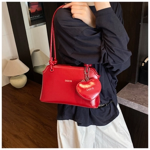 Close-up of stylish red underarm bag with a matching heart-shaped coin purse and logo