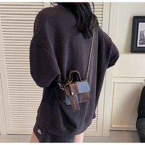 Detail view of contrast stitching mini square bag with denim and leather texture