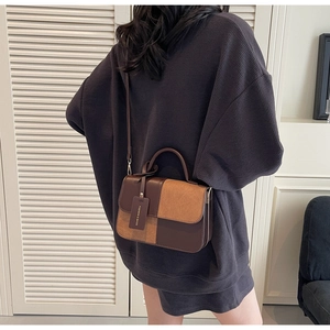 Detail showing contrast stitching and suede texture on a vintage brown crossbody bag