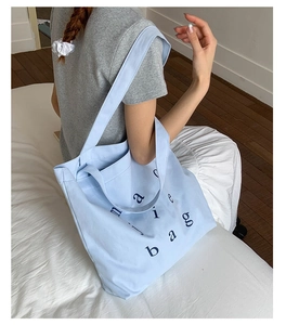 Detail of light blue canvas tote bag showing magic bag lettering and shoulder strap
