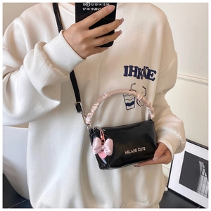 Détail du petit sac noir avec poignée froncée en satin rose et charm nœud rose