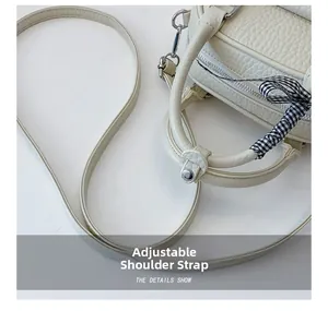 Detail of cream shell bag featuring pebble leather texture and adjustable strap