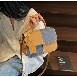 Detail of color-block tote bag featuring brown leather and blue denim patchwork
