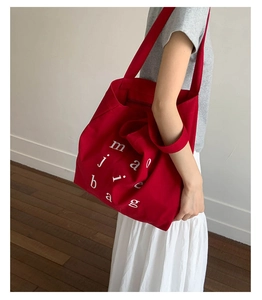 Detail view of large red canvas tote bag with artistic white letter print design