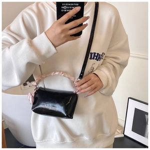 Détail du sac polochon noir brillant avec poignée plissée rose et breloque en cœur