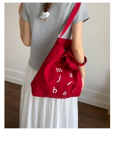 Detailed macro shot of red canvas tote bag with white letter prints on durable fabric