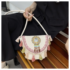Detail of bohemian woven bag with colorful beads and long pink and green tassels