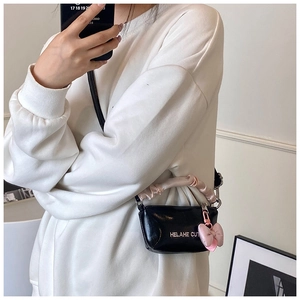 Détail du sac à main noir brillant avec poignée à volants rose et breloque nœud décoratif