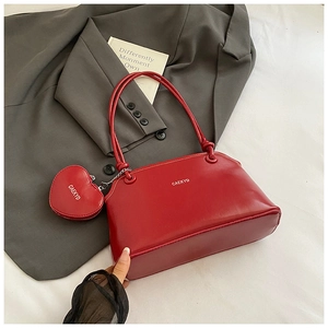 Detail of red leather underarm bag with zipper closure and heart-shaped coin purse attachment