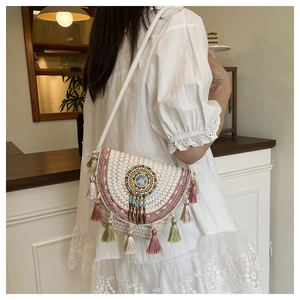 Detail of bohemian woven crossbody bag with colorful embroidery and long layered tassels