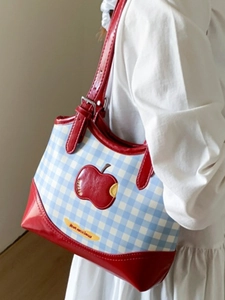 Cute blue checkered tote bag with red apple motif and trim, worn by a model in white dress