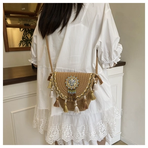 Bohemian woven crossbody bag with colorful tassels and beads on a female model