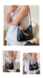 Detail of black faux crocodile skin bag with silver zipper and brown bear keychain charm