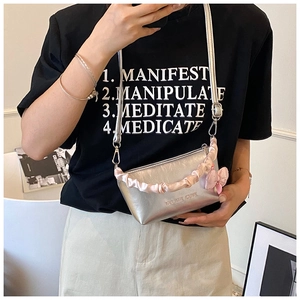 Détail du sac à main argenté métallisé avec poignée en satin froncé rose et joli nœud