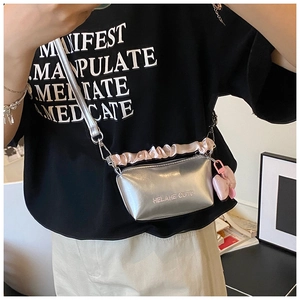 Détail du sac polochon argenté avec bandoulière à volants roses et breloque noeud mignon