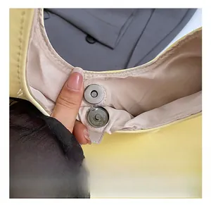 Close-up of yellow leather bag with silver magnetic snap and micro-grain lining