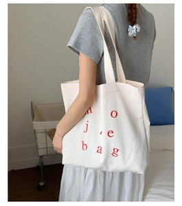 Detailed back view of a large cream canvas tote bag with red lettering on shoulder