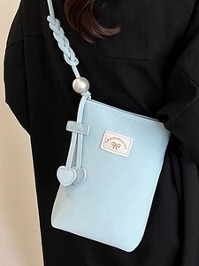 Light blue crossbody phone bag with pearl charm and woven strap on model side view