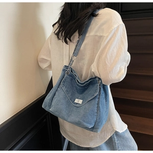 Detail view of washed denim hobo bag with silver twist lock and chain strap on shoulder