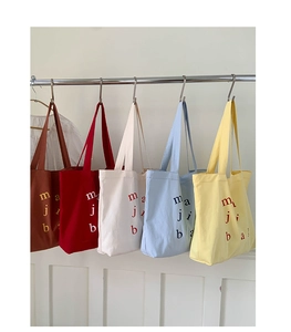 Detail view of large canvas tote bags in five vibrant colors with letter prints