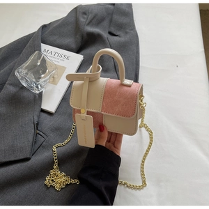 Detail of a mini two-tone crossbody bag with pink suede panels and a gold chain strap