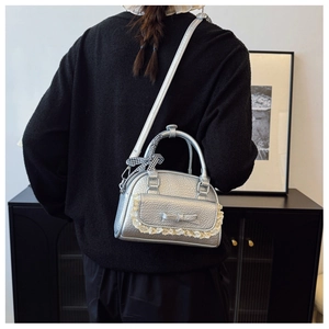 Detail of silver metallic shell bag with lace trim and patterned scarf handle on model
