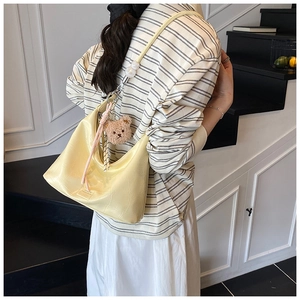 Detail of light yellow crocodile pattern crescent bag with white large pearl strap