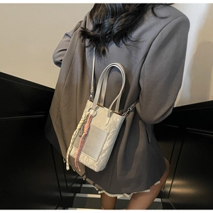 Détail du sac bandoulière gris marbré avec étiquette mode et breloque ruban zèbre