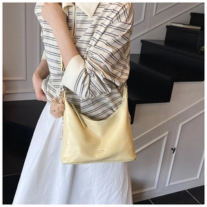 Model wearing a yellow crocodile embossed crescent shoulder bag with a cute bear charm