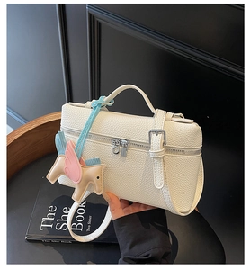 Dettaglio borsa a mano in pelle bianca motivo litchi con ciondolo a forma di cavallo