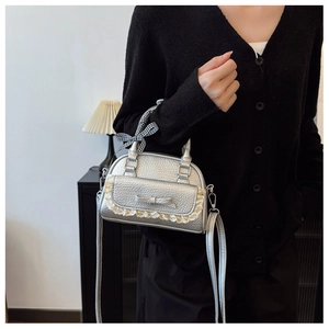 Detail of silver dome handbag with lace bow pocket and checkered ribbon handle