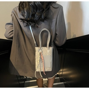 Détail du sac à main gris avec motif marbre, doubles poignées et breloque en perles
