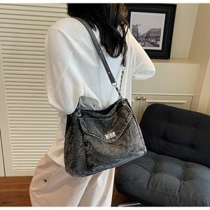 Detail of grey washed denim shoulder bag with silver turn-lock and chain strap