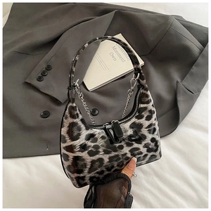 Detailed macro of shiny leopard print patent leather bag with silver chain and zipper