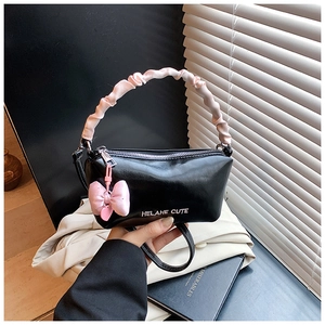 Détail d'un sac oreiller noir brillant avec poignée en soie rose et noeud coeur