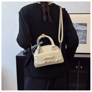 Chic cream shell bag with lace trim and bow detail worn on model's back