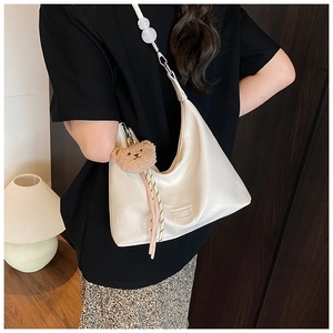 Detail of white crocodile pattern crescent bag with plush bear charm and beaded strap