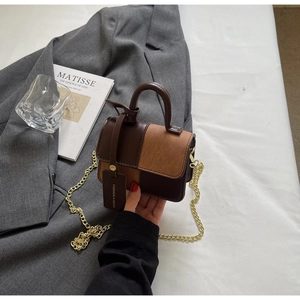 Detailed close-up of brown color-block square bag with gold chain on grey blazer