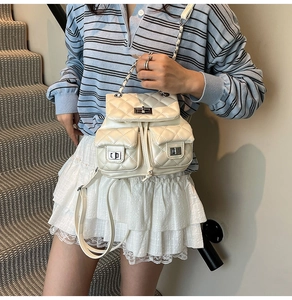Detail of creamy quilted mini backpack with silver chain straps and metal twist lock