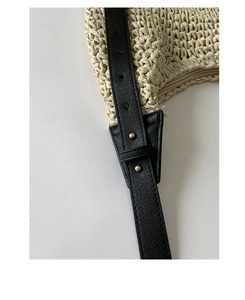 Detail of cream straw woven tote with black leather strap and gold rivet adjustment