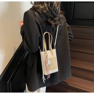 Détail du sac bandoulière crème avec poche avant marron et breloque en corde tressée
