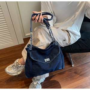 Detail view of washed denim fabric bag featuring silver twist lock and chain strap