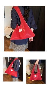Detailed view of large red velvet tote bag with minimalist white brand label and glossy finish