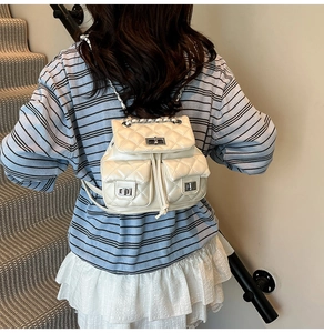 Detail of cream mini backpack featuring quilted diamond pattern and silver twist-lock pockets