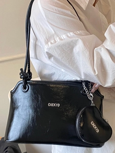 Glossy black shoulder bag with heart charm and minimalist knot detail for women