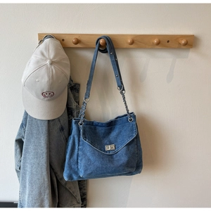 Detail of blue denim hobo bag with silver swivel clasp hanging on a wooden hook